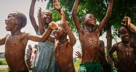 Close Up on a Group of Happy and Innocent Black Children Playing and Enjoying the Blessing of Rain...