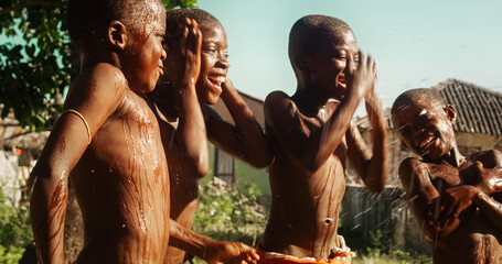 Group of African Kids Jumping and Laughing when Water Gets Poured on Them. Happy and Innocent Black...