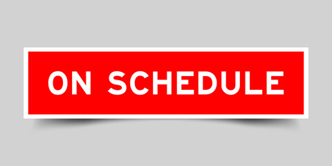 Red color square shape sticker label with word on schedule on gray background