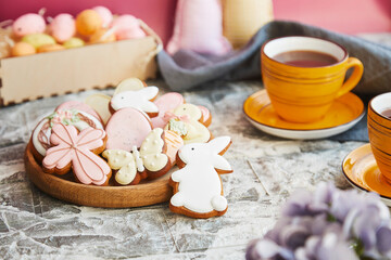 Obraz na płótnie Canvas Aesthetics Easter glazed cookies and cup of tea on the decorated holiday table