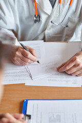 vertical shot of male doctor writing medical prescription to patient