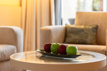 Red and green apples on a coffee table in an interior in beige tones
