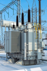 Power transformer in a high-voltage electrical substation outdoors in winter.