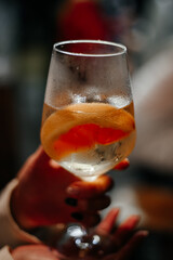 Girl in a bar holds a glass of martini with a piece of grapefruit, a cold alcoholic drink