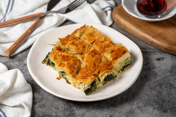 Spinach pastry. Traditional Turkish cuisine delicacies. Spinach pie made with breakfast phyllo on a dark background