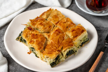 Spinach pastry. Traditional Turkish cuisine delicacies. Spinach pie made with breakfast phyllo on a dark background