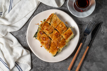 Spinach pastry. Traditional Turkish cuisine delicacies. Spinach pie made with breakfast phyllo on a dark background. Top view
