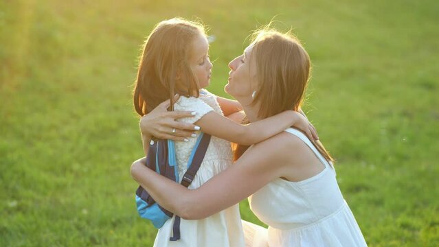 Happy mother meets excited daughter first-grader after school. Stylish woman asks girl about first day at elementary school after summer holidays