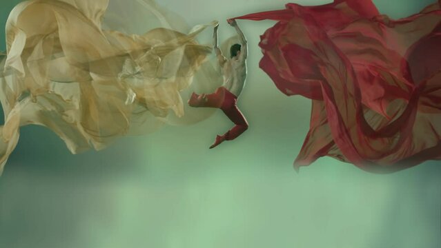 Art dance moves with long fabrics . Few shots of the powerful psychological contemporary ballet dancing movements with large textile materials . People dancing , flying , jumping . Growth of cloth