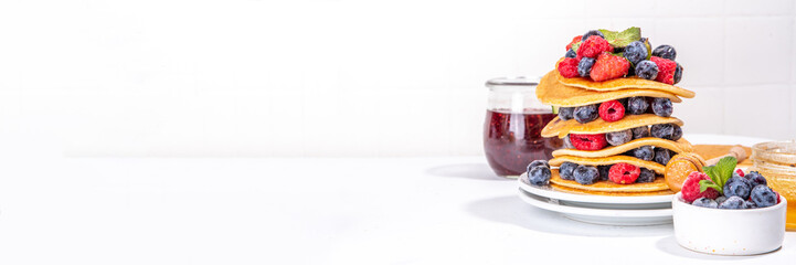 Healthy summer morning breakfast pancakes with fresh berry. Stack of traditional pancakes with blueberry, raspberries, honey. Healthy morning breakfast on white sunny background