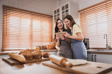 Female and female or LGBT couples are happily cooking bread together in the home kitchen.