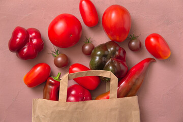 Layout of fresh red tomatoes and peppers. The vegetables are spilled out of a paper bag. Shopping Concept.