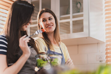 Female and female or LGBT couples are happily cooking bread together in the home kitchen.