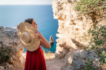 A woman in a red flying dress fluttering in the wind, against the backdrop of the sea.
