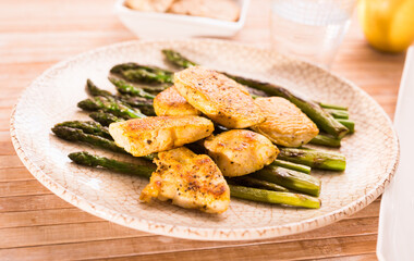 cooked dish. Chicken nuggets with green asparagus on plate