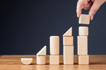 Build a growth stair with different geometry wood toys, creativity and success, and different forms of identity joined together to reach to the top, or education concept