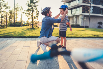 Stock photo of a father helping his son put on a bicycle helmet.