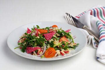 Salad with orzo pasta, arugula, tomatoes, and salami