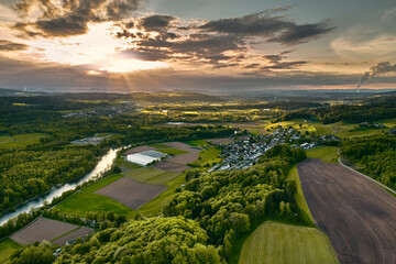 Dramatische Wolkenstimmung in der Flusslandschaft der Reuss. Sonnenstrahlen sorgen für helle Spots in der grünen Landschaft.