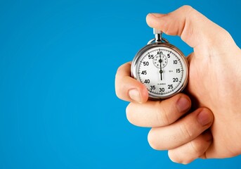 Classic clock in a human's hand on color background