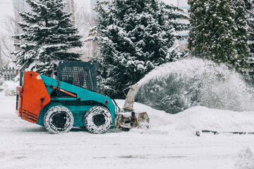 City municipal services are engaged in snow removal. Machines for cleaning snow. A tractor cleans the parking from snow