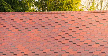 Roof with red bitumen shingles. Modern types of roofing materials