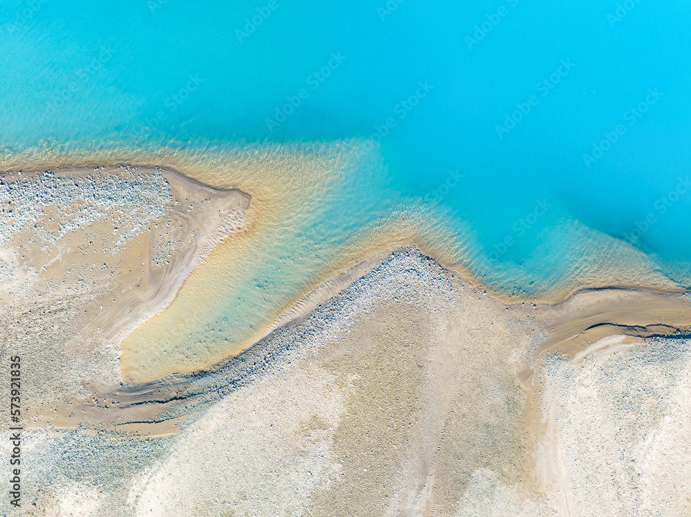 Wall mural clear azure water in a mountain lake. the shore with stones. view of the water from a drone. landsca