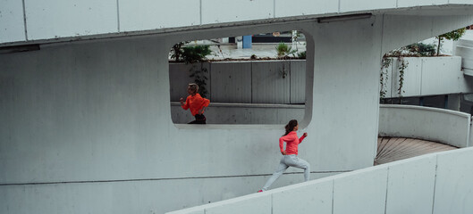 Two women in sports clothes running in a modern urban environment. The concept of a sporty and healthy lifestyle