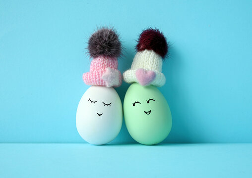 Happy eggs in hats laughing. Easter holiday concept with cute eggs with funny faces.