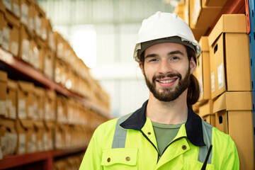 Portrait of handsome caucasian warehouse worker standing in large warehouse distribution center with laptop. Positive thinking