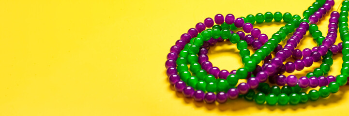 purple and green beads on yellow background Top view 2022 Mardi Gras Parade Schedule Mockup Copy space