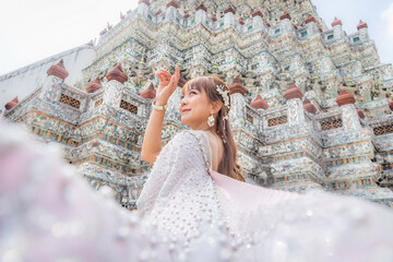 Close up of a young woman wearing traditional Thai dress with accessories standing at Wat Arun, a popular place for tourists around the world. Bangkok Thailand