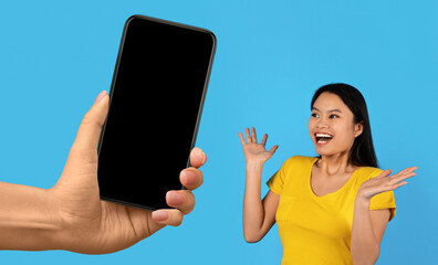 Surprised Japanese Woman Looking Aside At Blank Smartphone In Giant Hand