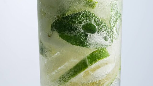 Cold lemonade mojito cocktail carbonated drink. Closeup refreshing soda tonic fizzy sparkling water, mint and lemon in glass, ice cubes. Slice of lemon, mineral bubbles. Healthy dietary nutrition.