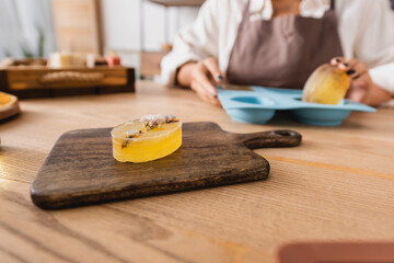 selective focus of herbal soap on chopping board near cropped african american woman with silicone mold on blurred background.