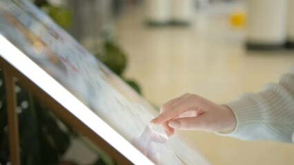 Woman looking for information and store location on digital touch screen in shopping mall 4K