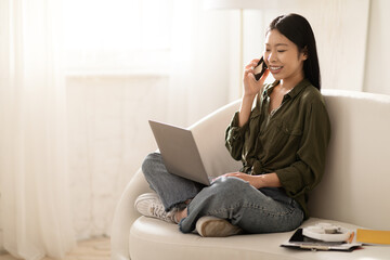 Happy asian lady freelancer working from home, using laptop