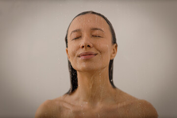 Young woman under the trickles of water in pleasure shower. Beautiful girl under the spray of water...
