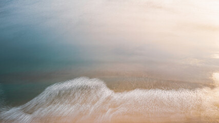 Sunrise seascape of soft curving white waves over beach sand and blue ocean horizon in Daytona Beach, Florida, long exposure aerial photography of painting and zen-like landscape of abstract nature