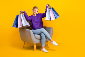 Full size portrait of nice positive girl sit chair arms hold packages empty space isolated on...