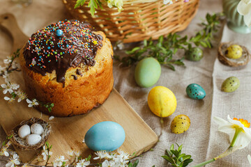 Natural dyed easter eggs and homemade easter bread on rustic table with spring blossoms and linen napkin. Top view. Traditional Easter food for basket