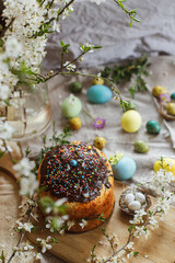 Happy Easter! Homemade easter bread and natural dyed easter eggs with spring flowers on linen napkin on rustic table. Traditional Easter food. Top view
