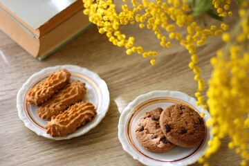 Scented candles, on the table. Selective focus.chocolate, cookies, cup of tea, books, e-reader, glasses and flowers on the table. Hygge at home. Selective focus.