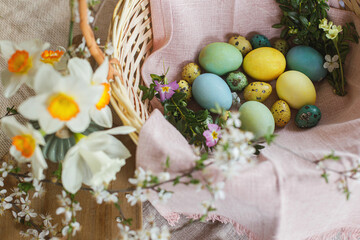 Happy Easter! Stylish natural dyed easter eggs with spring flowers on linen napkin in wicker basket. Traditional Easter food. Top view. Rustic Easter still life
