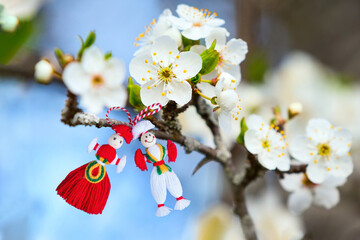 Bulgarian Martenitsa spring sign on blooming tree branch with flowers, holiday postcard background