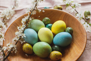 Stylish natural dyed easter eggs on wooden plate with spring flowers on rustic table. Happy Easter! Rustic Easter still life