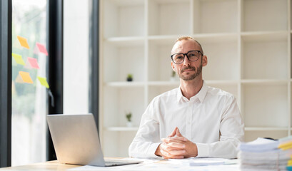Obraz premium Businessman using laptop computer in office. Happy middle aged man, entrepreneur, small business owner working online.
