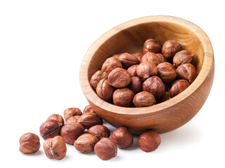 Hazelnuts fell out of a wooden plate on a white background. Isolated
