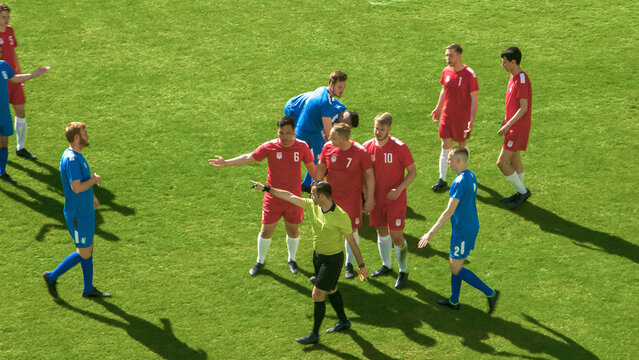 Soccer Football Championship Match: Referee Sees Foul, Gives Signal and Yellow Card, Players Circle him Upset, Arguing. International Tournament. Sport Broadcast Channel Television Concept.