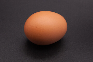 One chicken egg against a black background